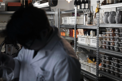 Restaurant worker organizing labeled ingredients and supplies in a commercial kitchen storage area.